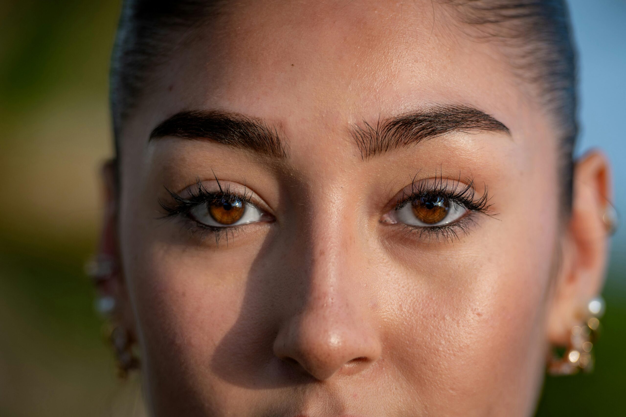 A detailed close-up of a woman's face highlighting her striking brown eyes and natural beauty.